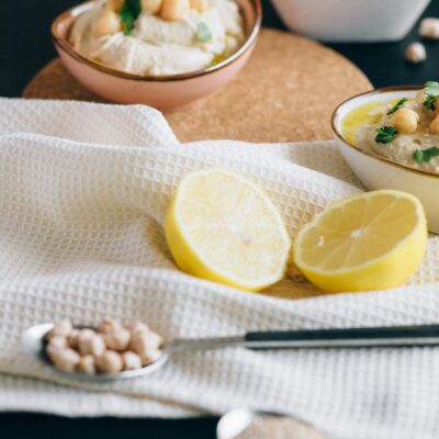 Close-up view of hummus bowls with chickpeas and sliced lemons, perfect for healthy eating.