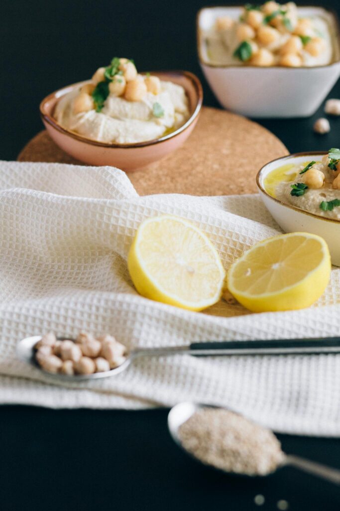 Close-up view of hummus bowls with chickpeas and sliced lemons, perfect for healthy eating.