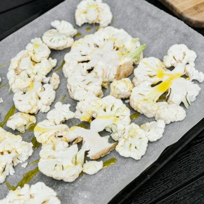 Sliced cauliflower with olive oil on a baking tray, perfect for a healthy meal.