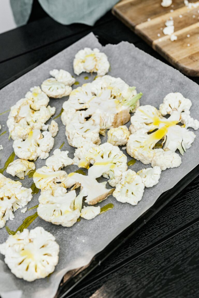 Sliced cauliflower with olive oil on a baking tray, perfect for a healthy meal.